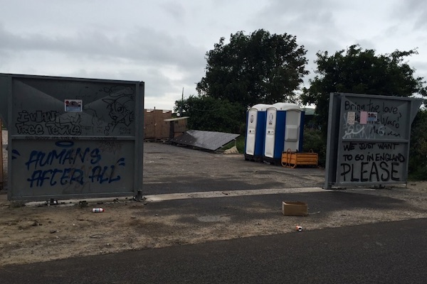 Graffiti along a metal fence on the outskirts of the Calais Jungle