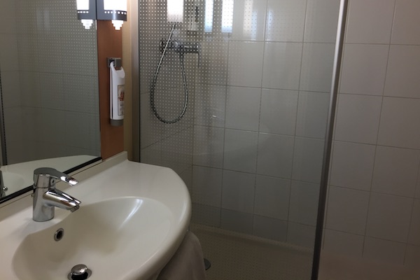 Bathroom sink and shower at Ibis Calais Hotel 